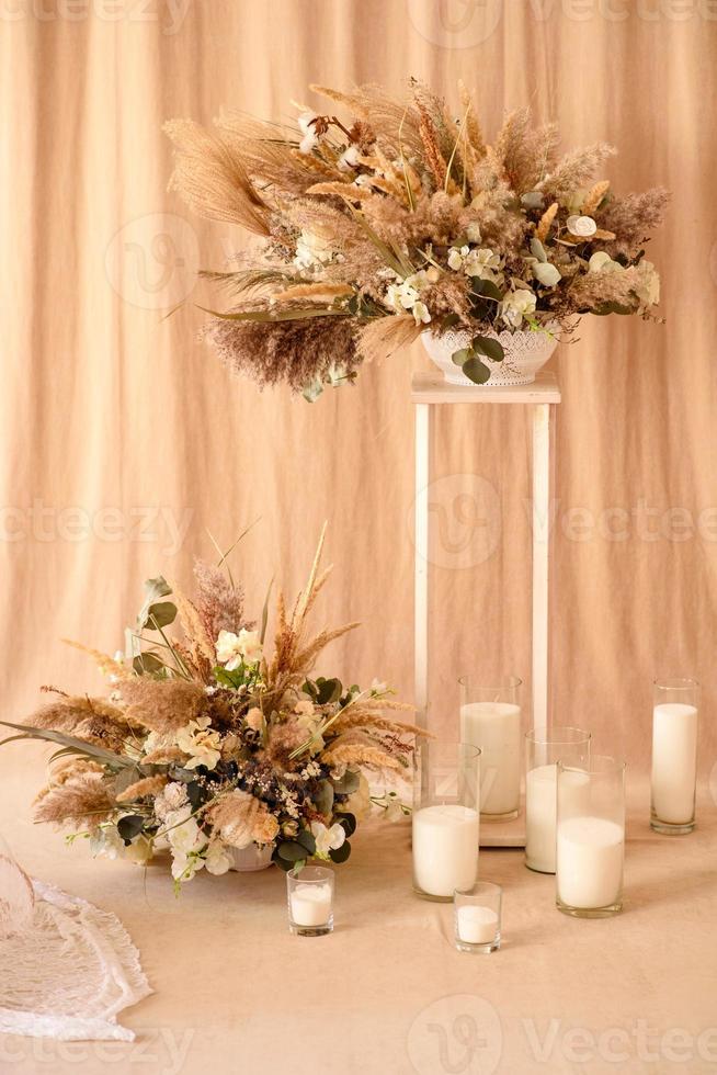 Decoraciones de hermosas flores secas en un jarrón blanco sobre un fondo de tela beige foto