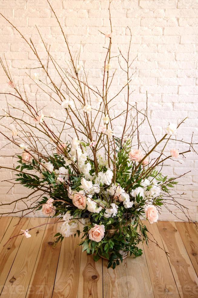 Decorations of branches with beautiful pink and white flowers in the basket against the background of a white brick wall photo