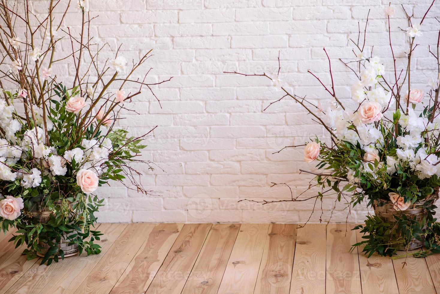 Decoraciones de ramas con hermosas flores rosas y blancas en la canasta con el telón de fondo de una pared de ladrillo blanco. foto