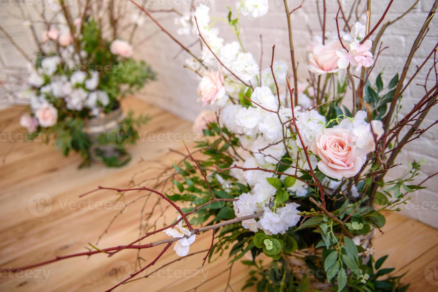 Decoraciones de ramas con hermosas flores rosas y blancas en la canasta con el telón de fondo de una pared de ladrillo blanco. foto