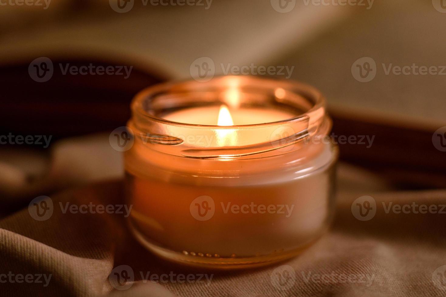 una vela encendida en una mesa de madera frente a un libro a media asta foto