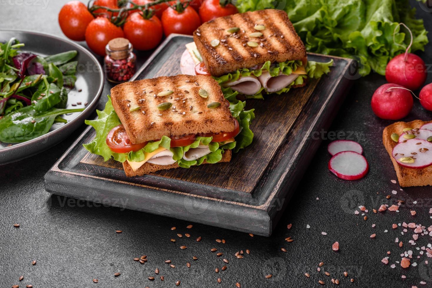 delicioso sándwich con tostadas crujientes, jamón, lechuga y tomates foto