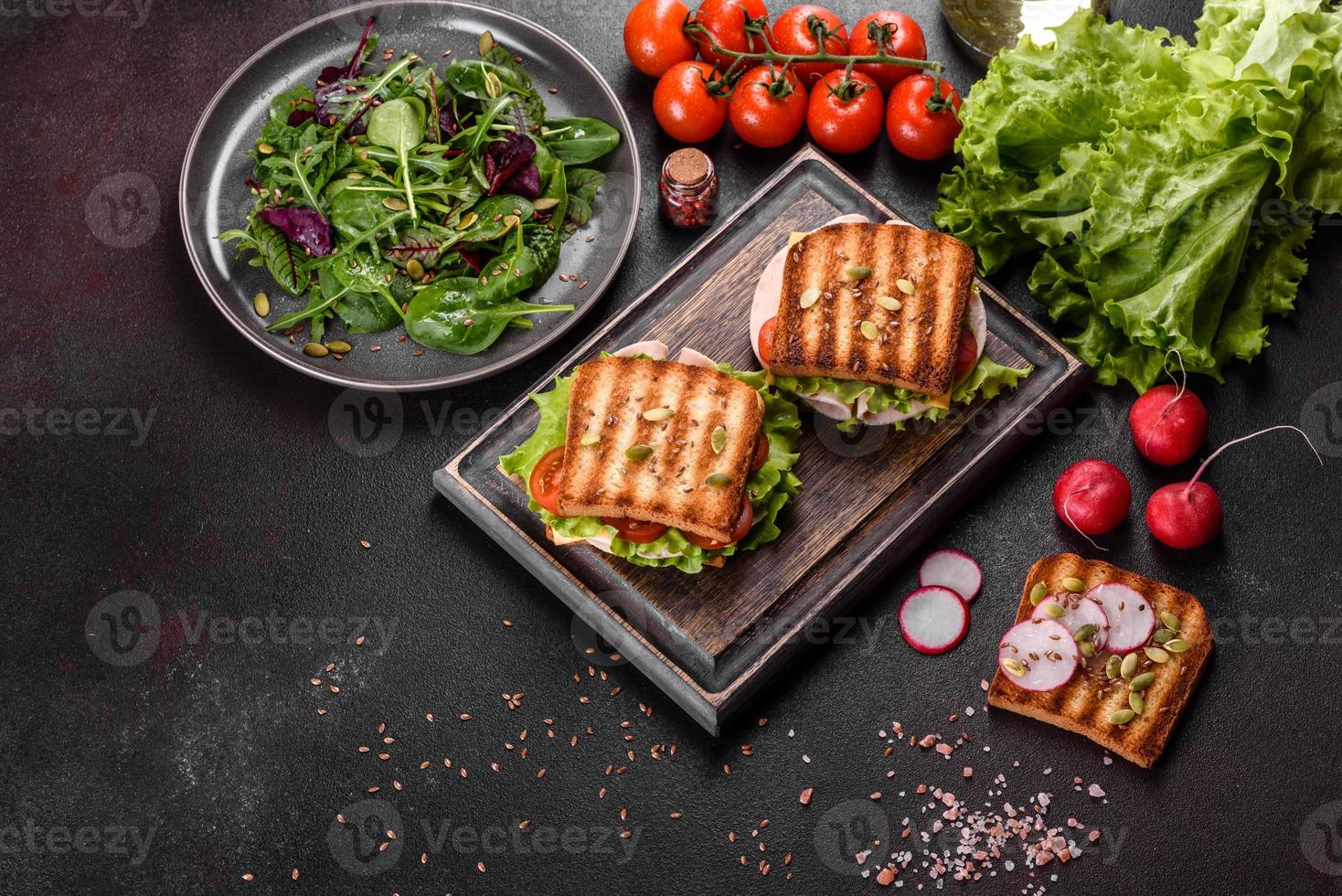 delicioso sándwich con tostadas crujientes, jamón, lechuga y tomates foto