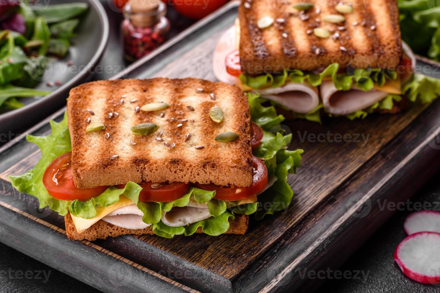 Delicious sandwich with crisp toast, ham, lettuce and tomatoes photo