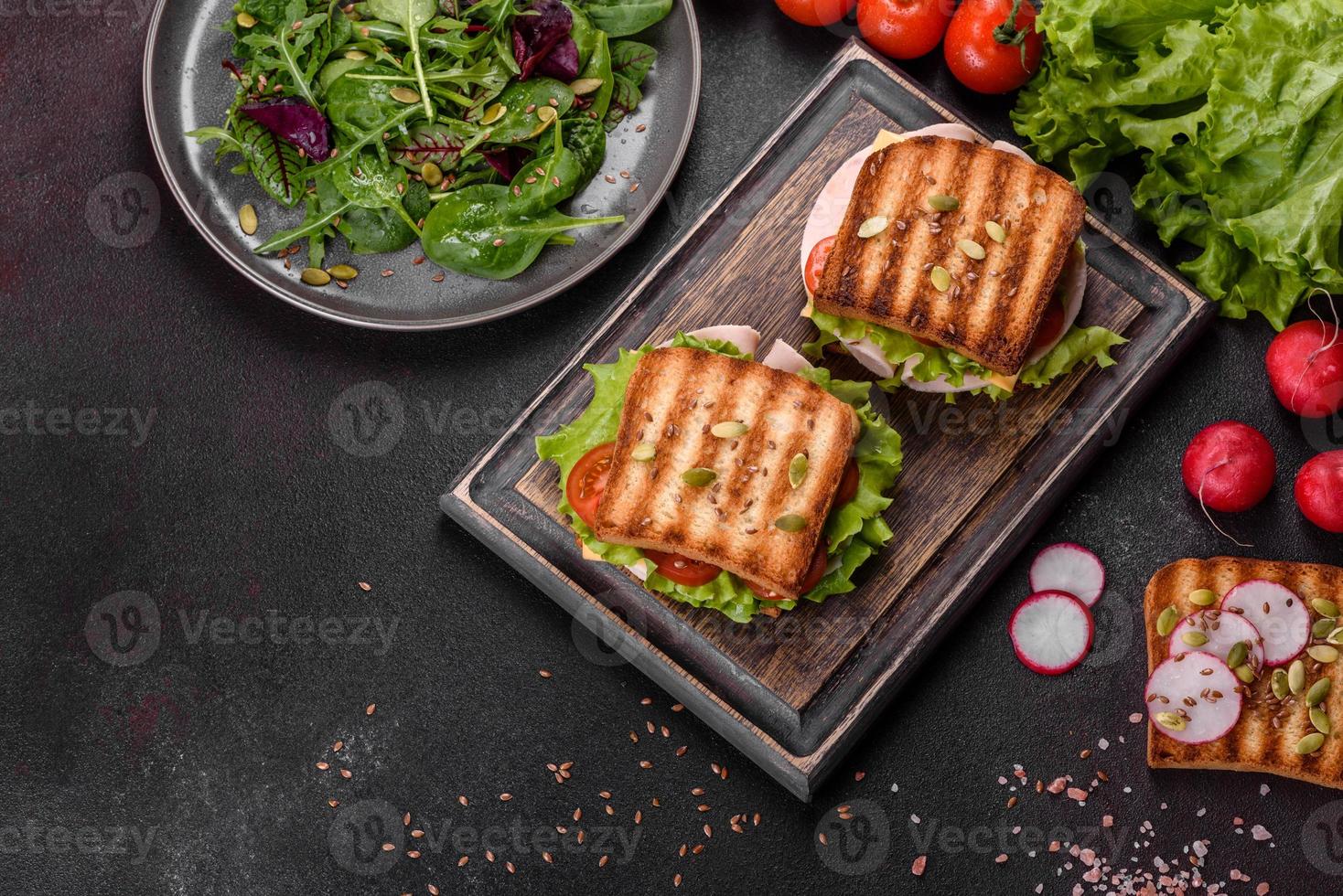 delicioso sándwich con tostadas crujientes, jamón, lechuga y tomates foto