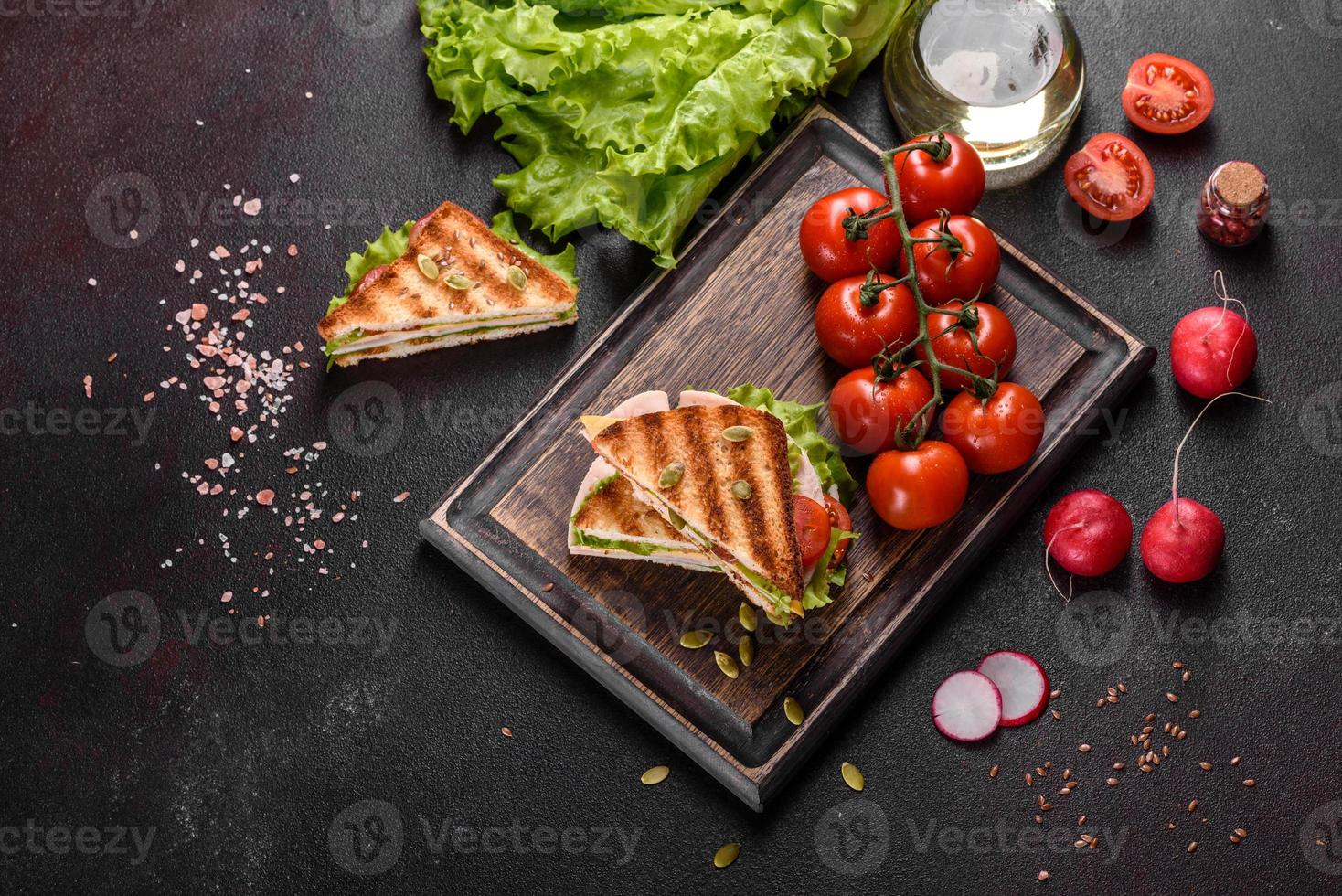 delicioso sándwich con tostadas crujientes, jamón, lechuga y tomates foto