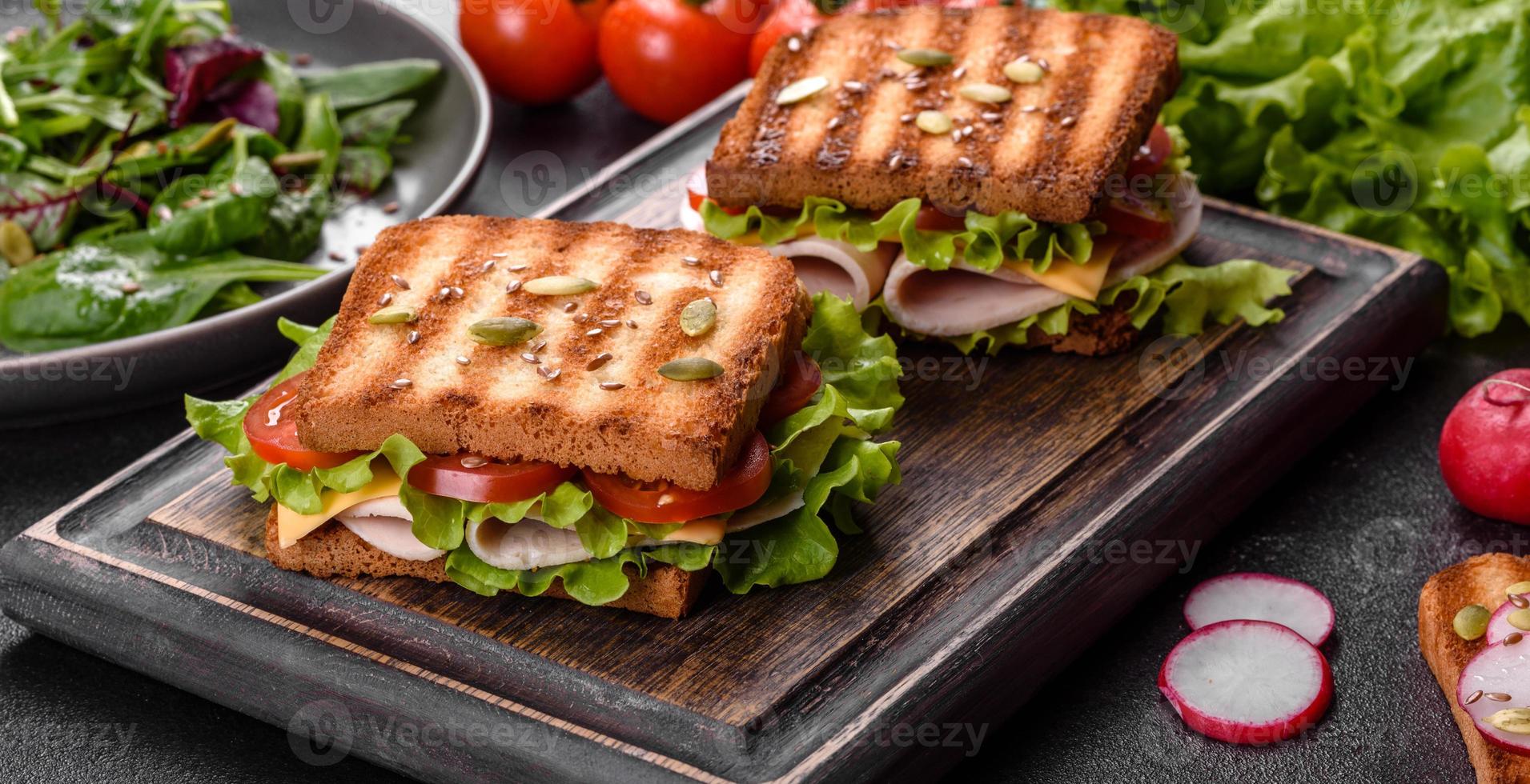 delicioso sándwich con tostadas crujientes, jamón, lechuga y tomates foto