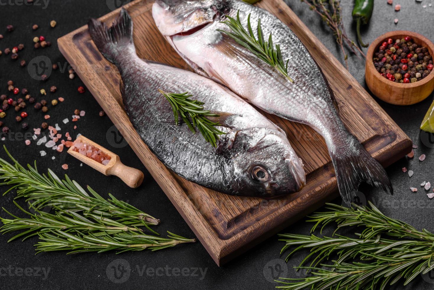 Pescado dorado crudo con especias para cocinar en la tabla de cortar. dorado de pescado fresco foto