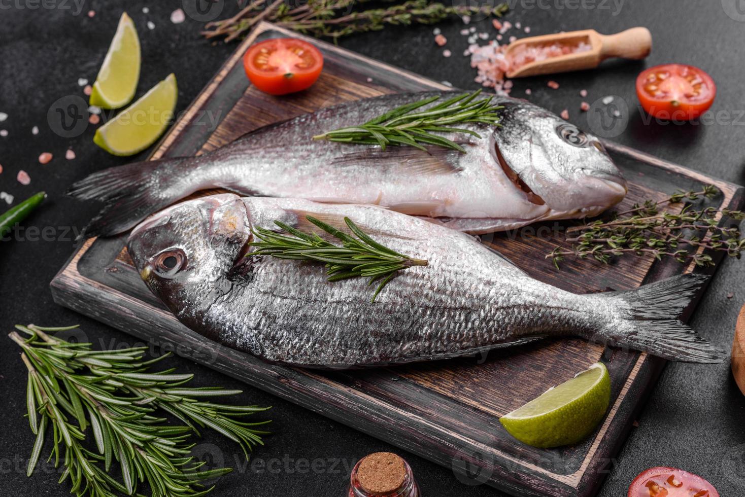 Pescado dorado crudo con especias para cocinar en la tabla de cortar. dorado de pescado fresco foto