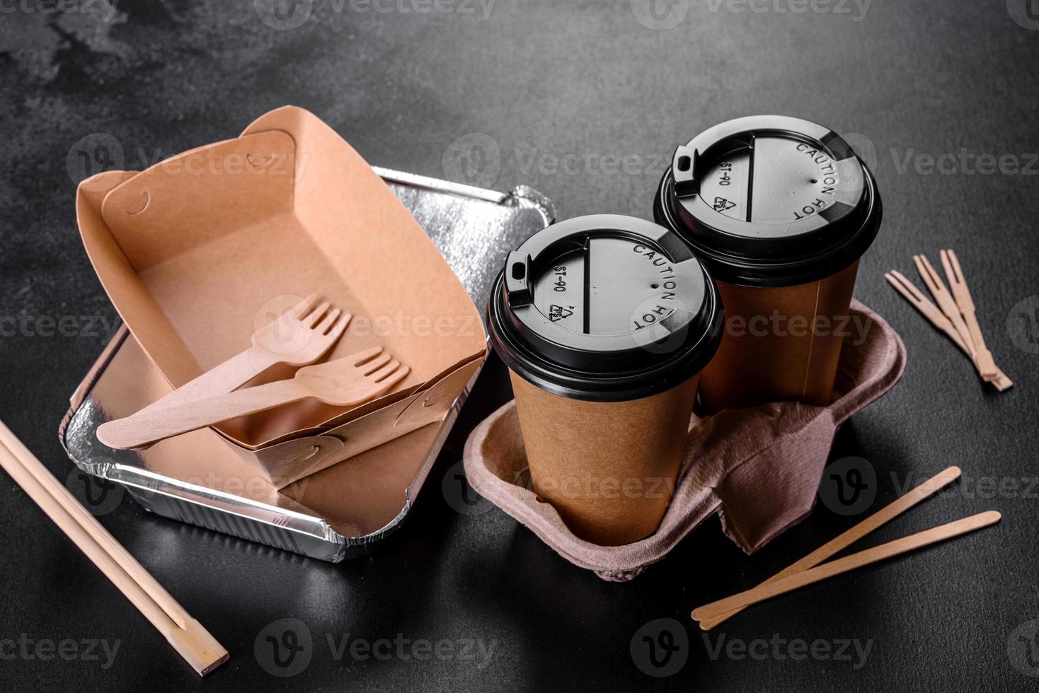 Disposable dishes made of environmentally friendly brown cardboard on a dark background photo