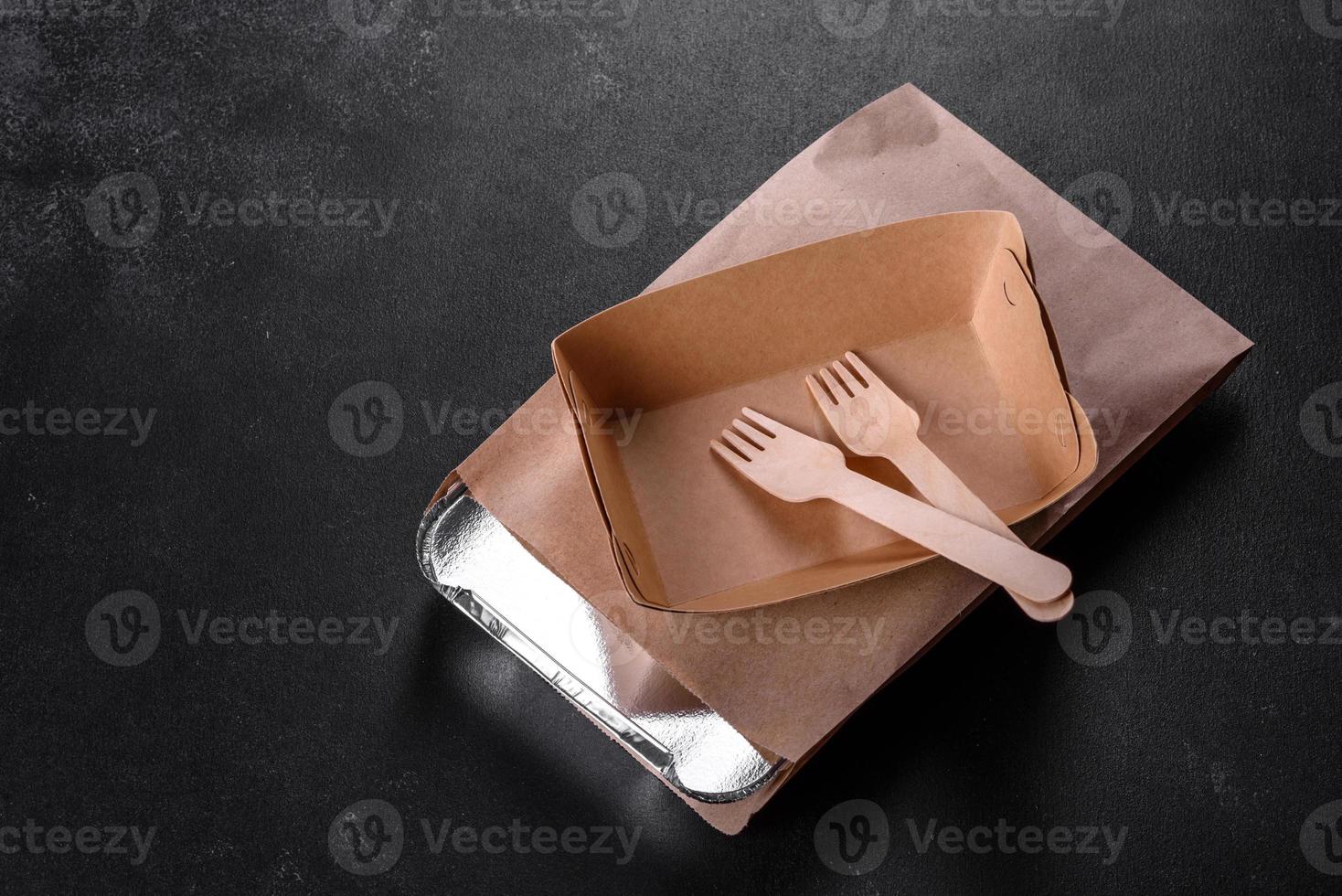 Disposable dishes made of environmentally friendly brown cardboard on a dark background photo