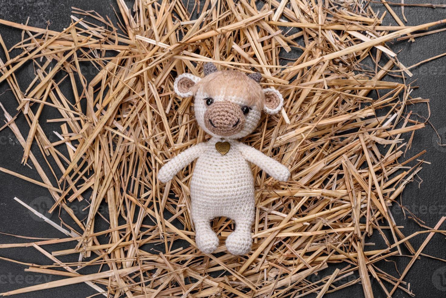 Knitted toy bull of light threads on a dark background photo