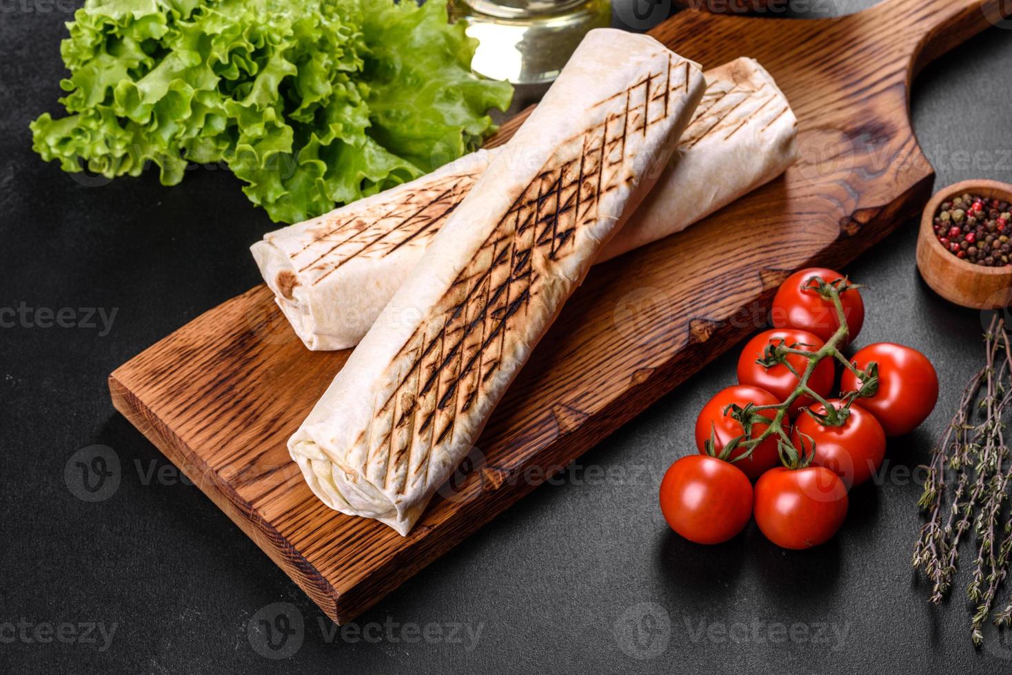 Delicious fresh shawarma with meat and vegetables on a dark concrete table photo