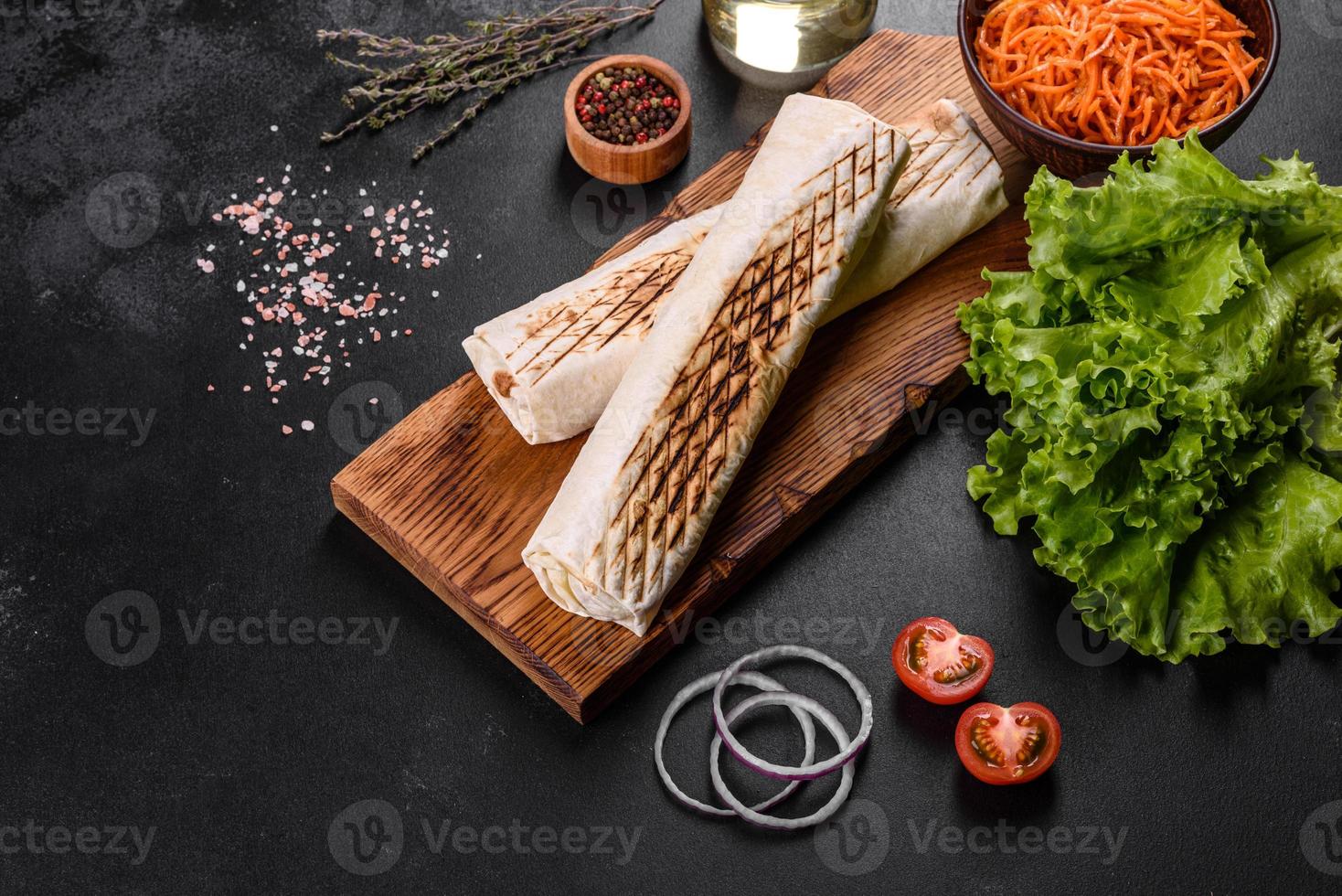 Delicious fresh shawarma with meat and vegetables on a dark concrete table photo