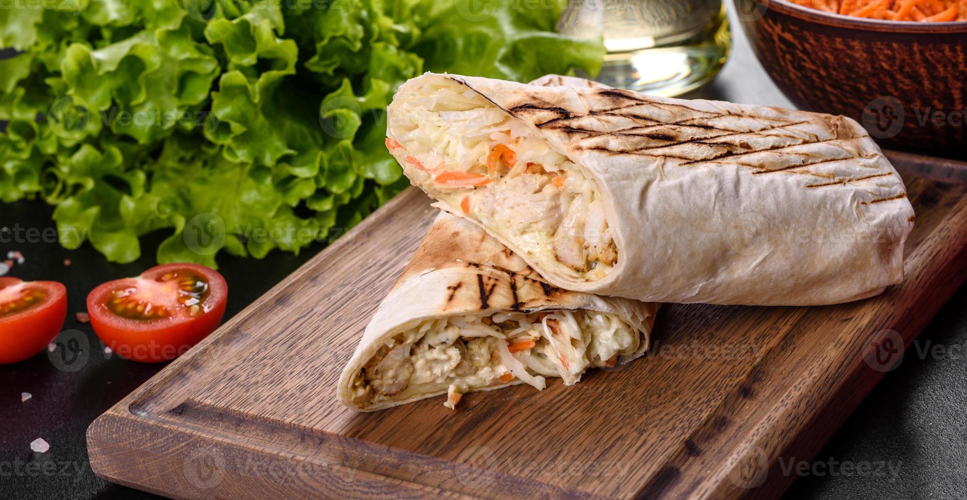 Delicious fresh shawarma with meat and vegetables on a dark concrete table photo