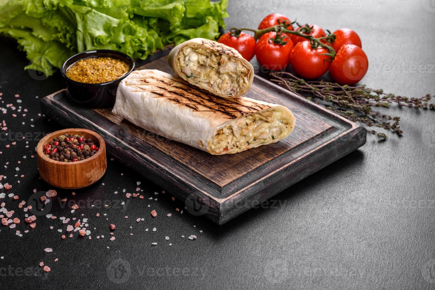 Delicious fresh shawarma with meat and vegetables on a dark concrete table photo