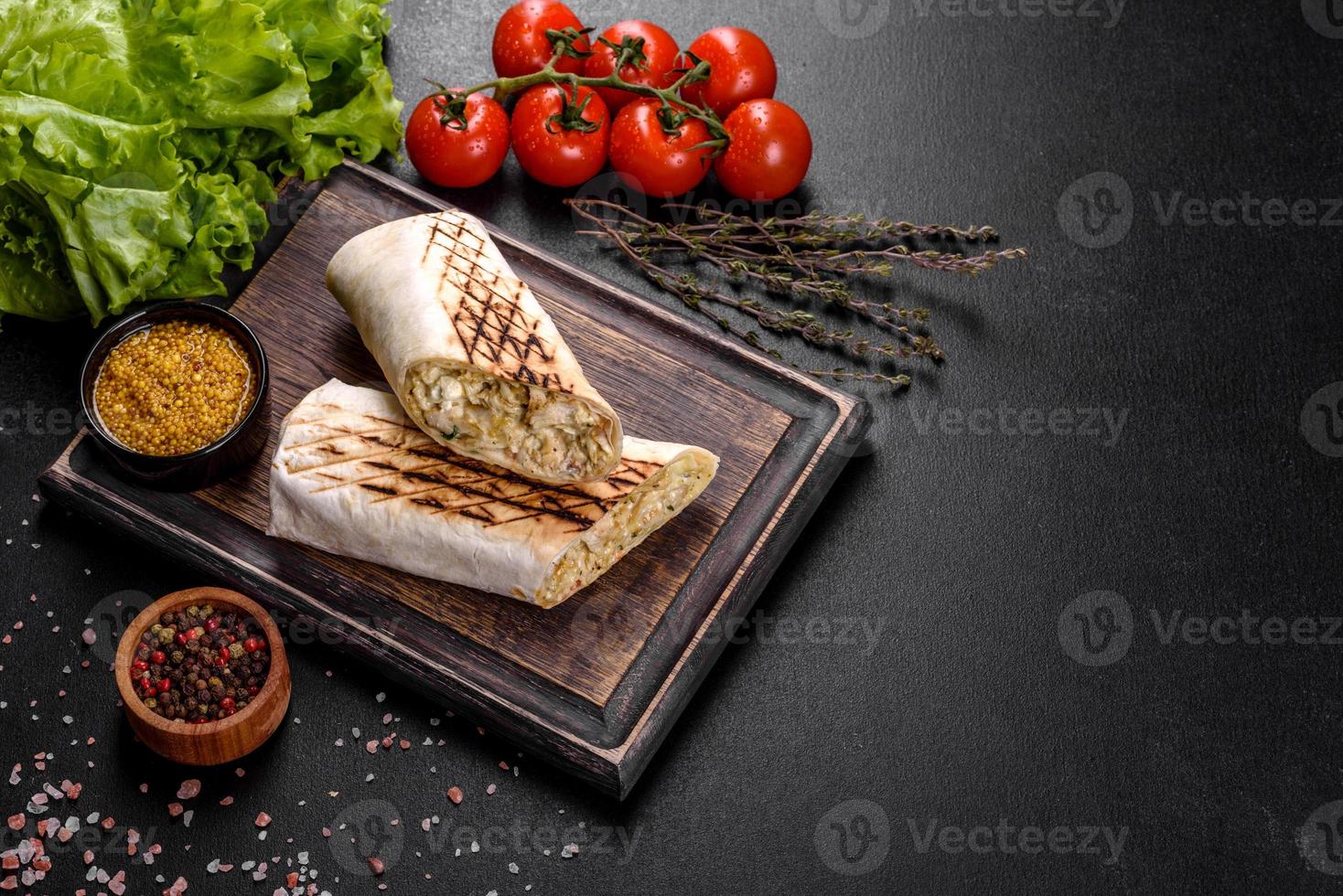 Delicious fresh shawarma with meat and vegetables on a dark concrete table photo