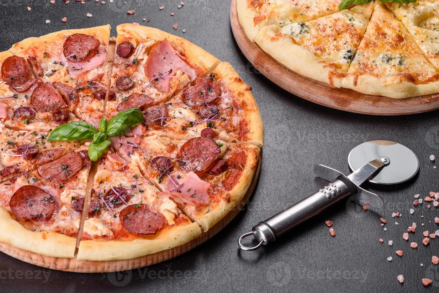 Deliciosa pizza recién horneada con tomates, salami y tocino sobre un fondo de hormigón oscuro foto