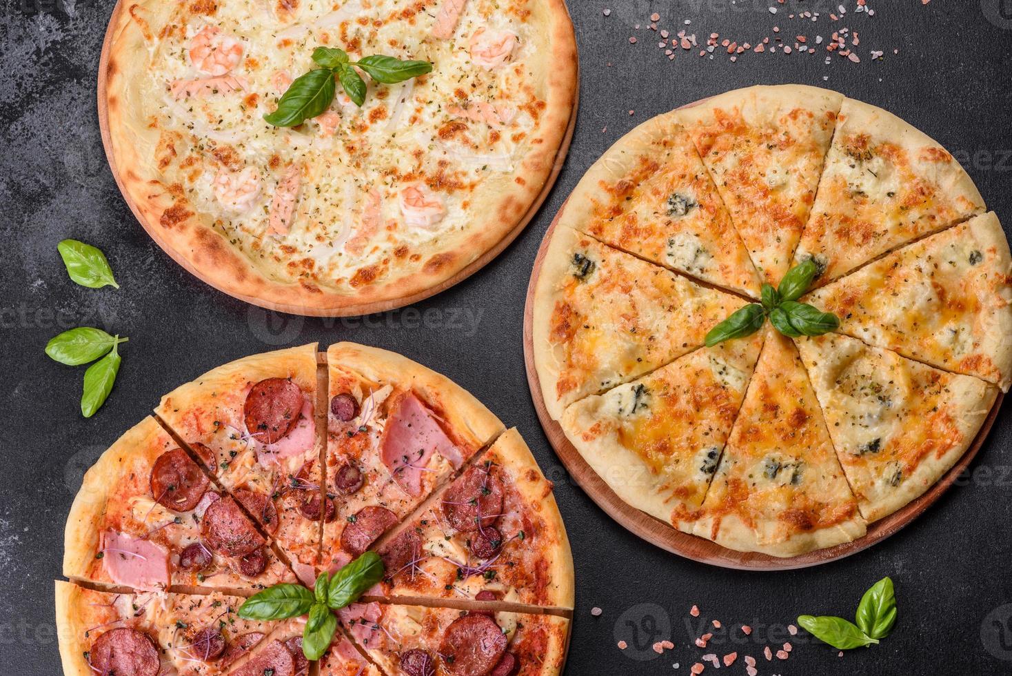 Deliciosa pizza recién horneada con tomates, salami y tocino sobre un fondo de hormigón oscuro foto