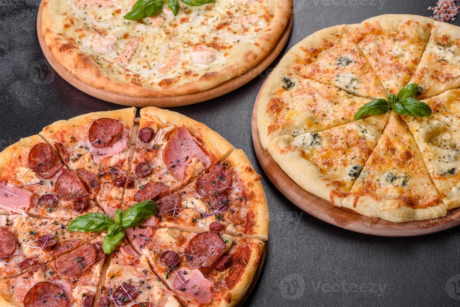 Delicious fresh oven pizza with tomatoes, salami and bacon on a dark concrete background photo