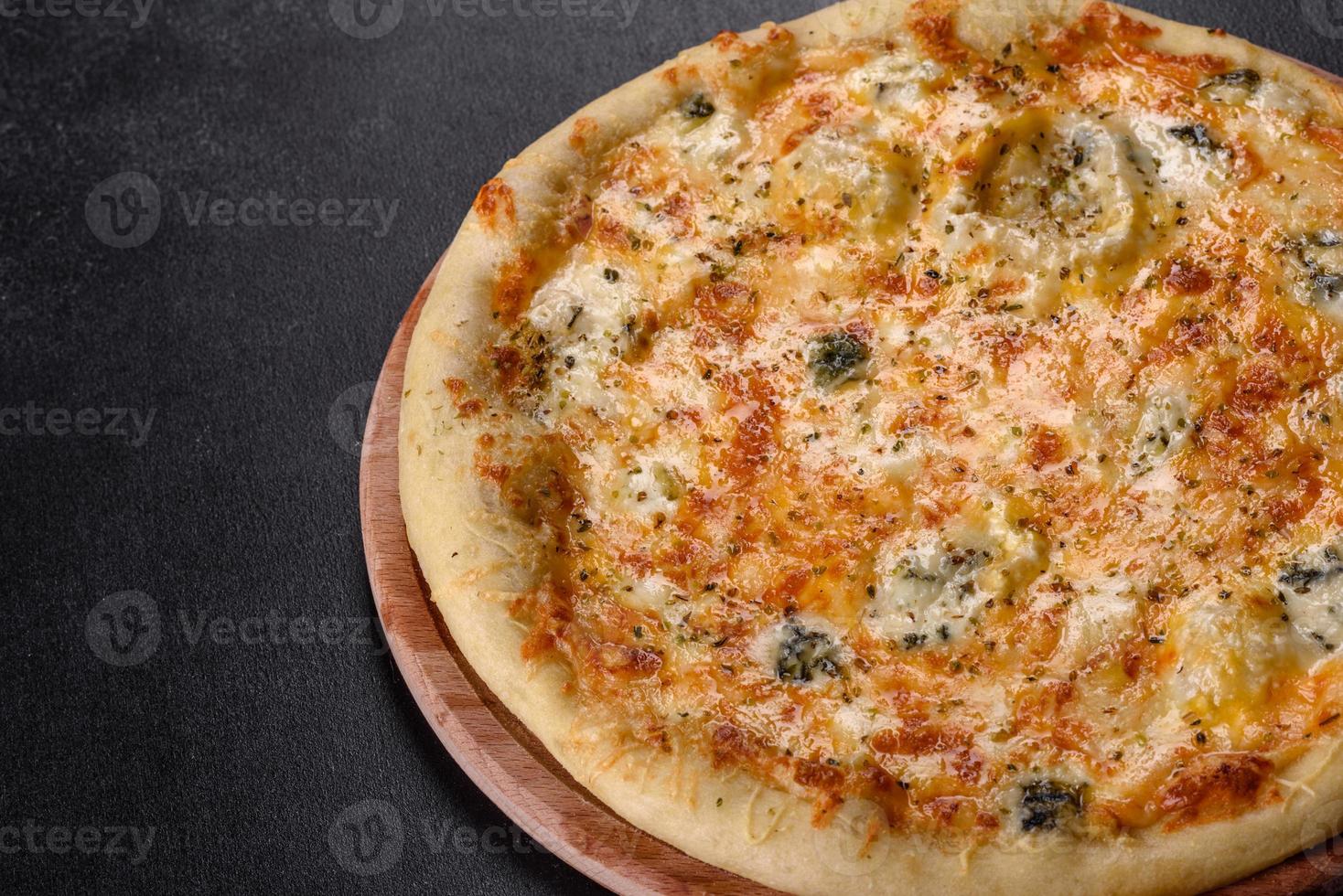 Sabrosa pizza fresca al horno con tomates, queso y champiñones sobre un fondo de hormigón oscuro foto