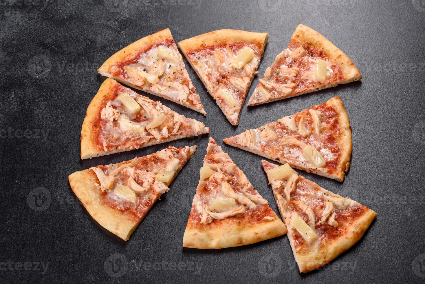 Tasty fresh oven pizza with tomatoes, cheese and pineapple on a dark concrete background photo