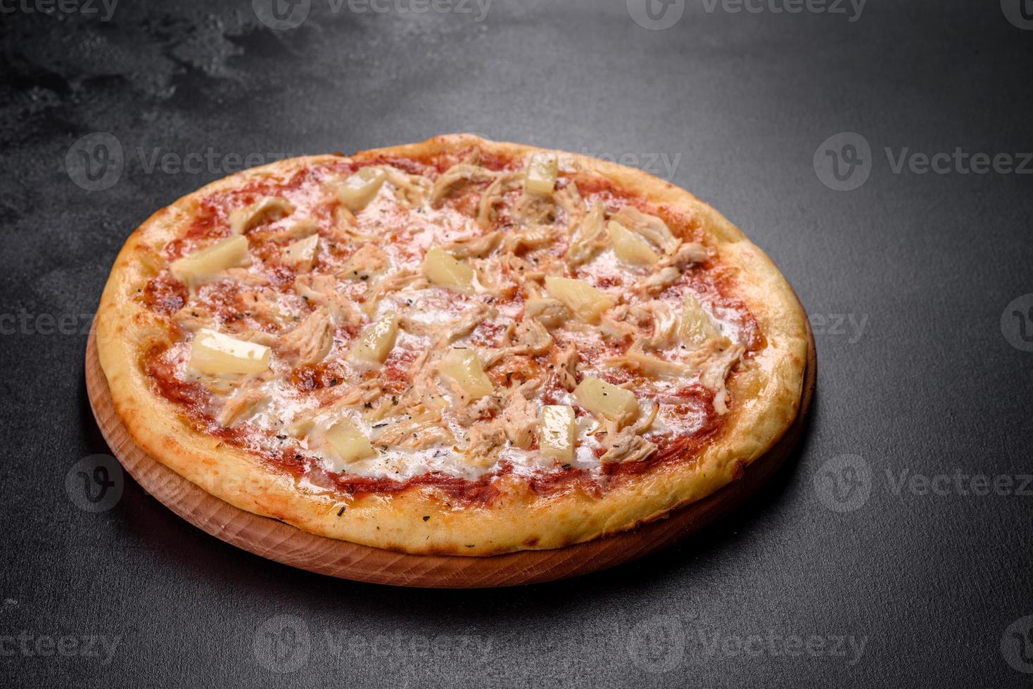 Tasty fresh oven pizza with tomatoes, cheese and pineapple on a dark concrete background photo