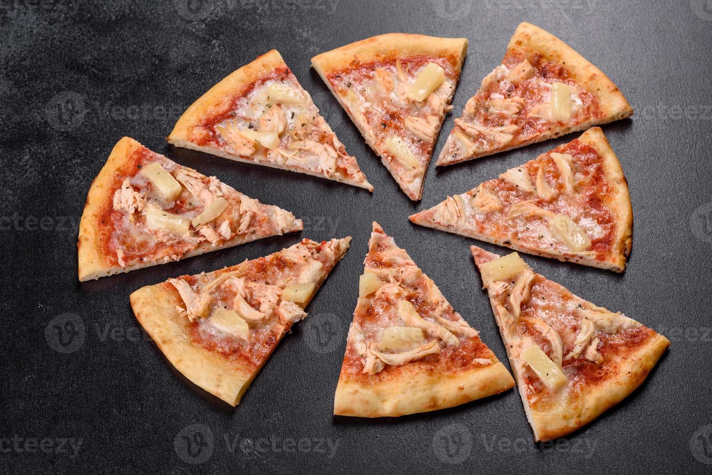 Tasty fresh oven pizza with tomatoes, cheese and pineapple on a dark concrete background photo