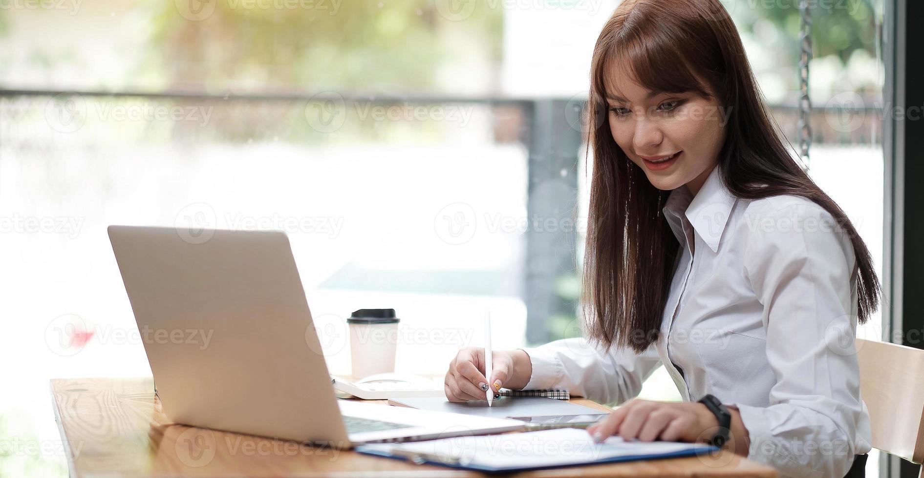 Retrato de una mujer joven y bonita que estudia mientras está sentado en la mesa foto