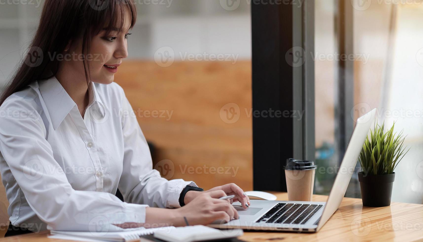 Retrato de una mujer joven y bonita que estudia mientras está sentado en la mesa foto