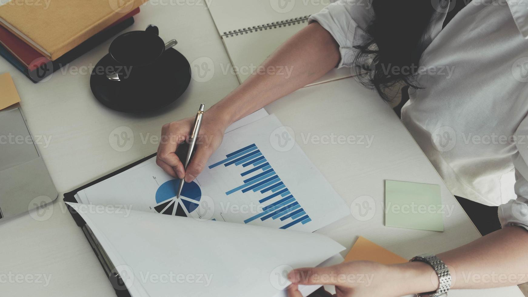 Businesswoman holding pen and pointing at financial paperwork photo