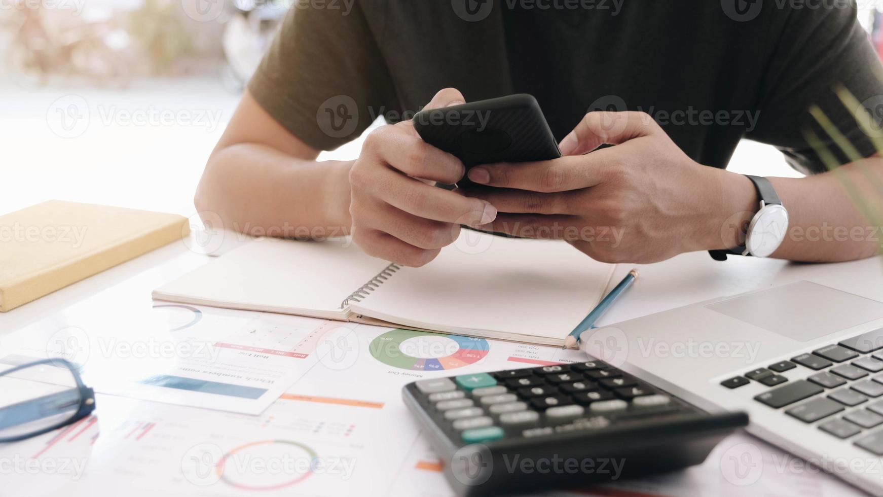 Man holding smartphone and using laptop computer at home photo