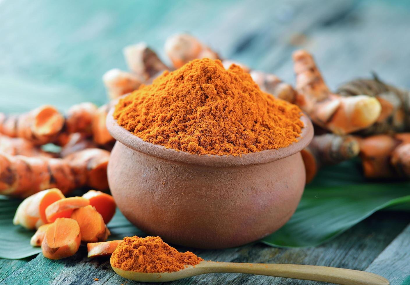 Turmeric powder in ceramic bowl on wooden background photo