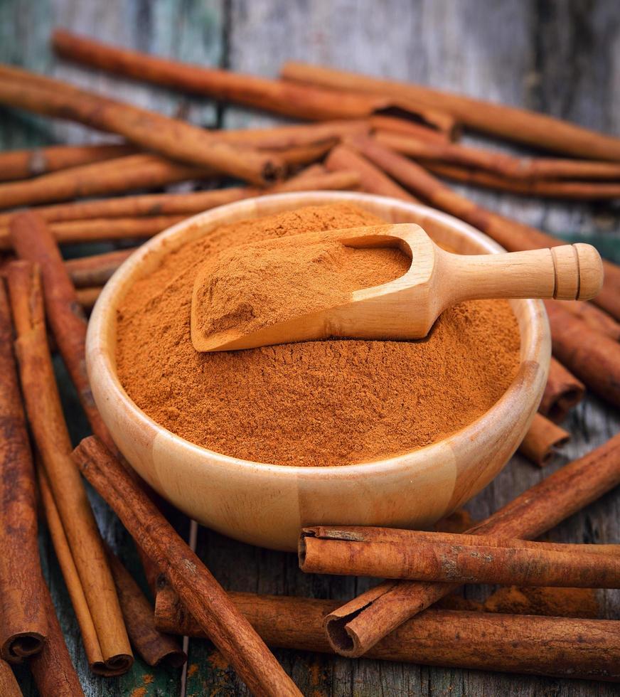 Palitos de canela y canela en polvo en el recipiente sobre la mesa foto