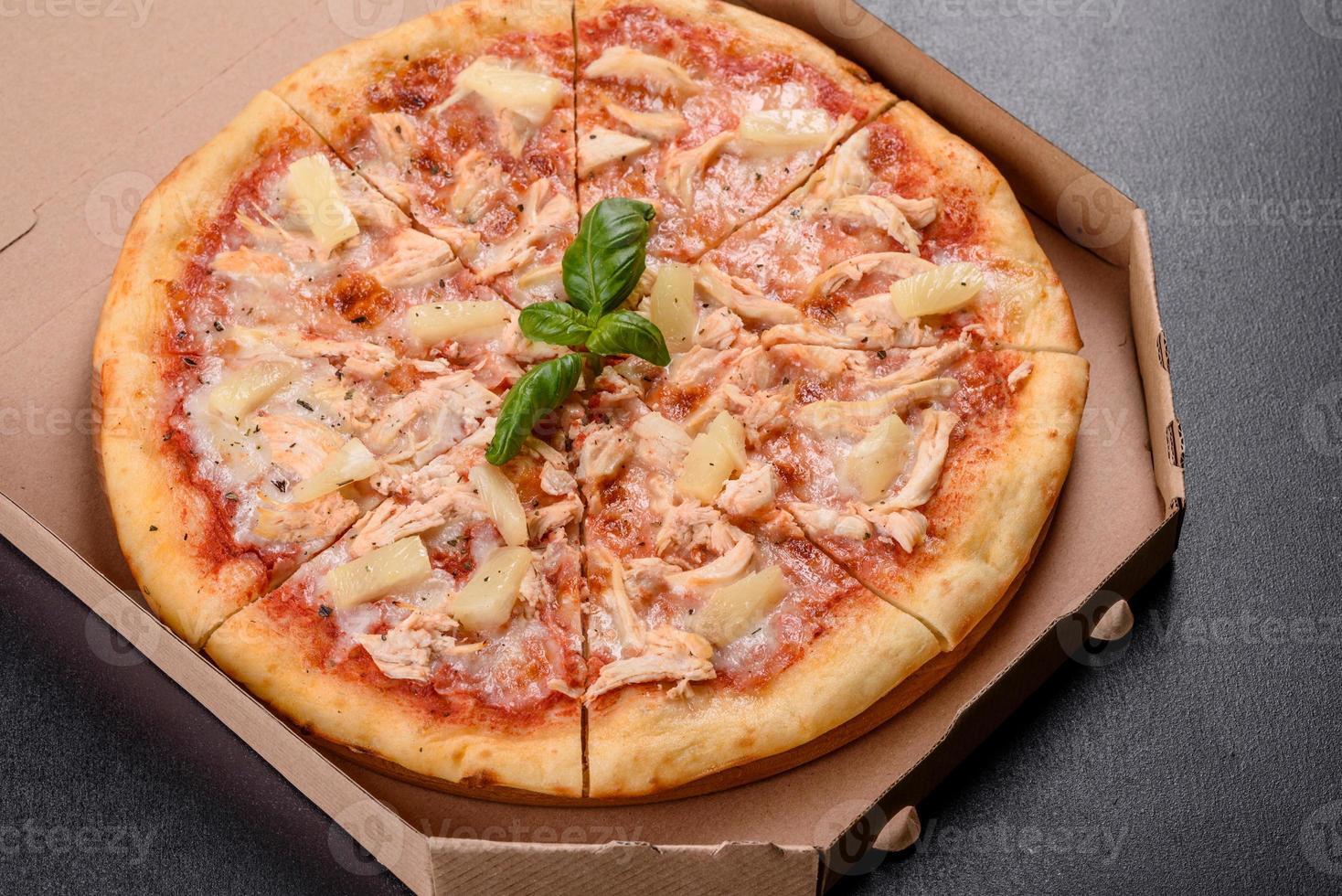 Sabrosa pizza recién horneada con tomate, queso y piña sobre un fondo de hormigón oscuro foto