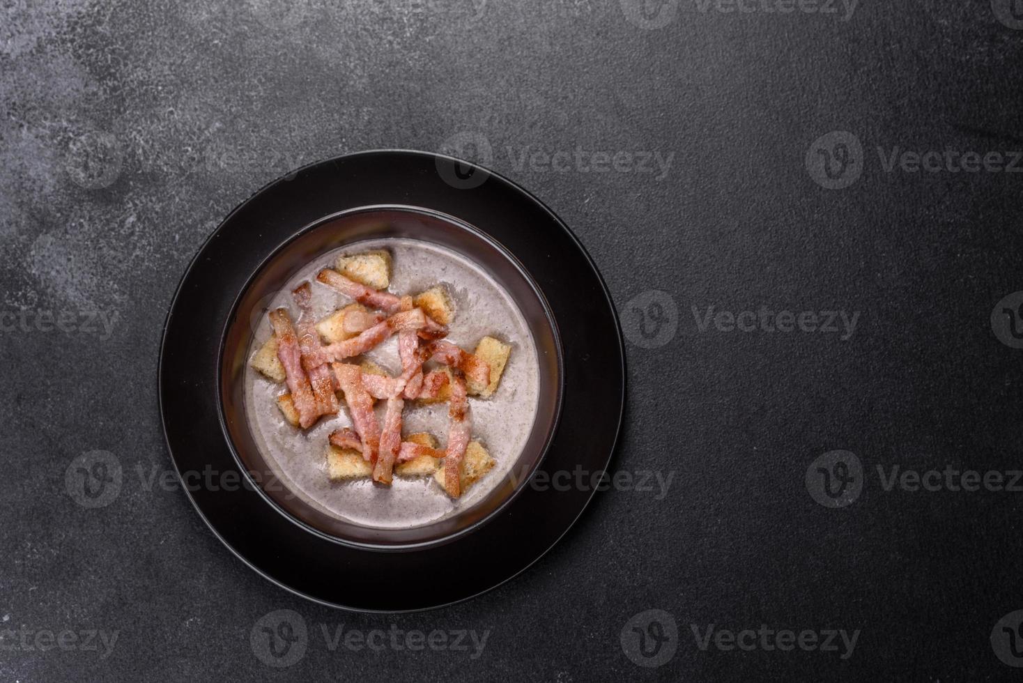 Fresh delicious hot puree soup with mushrooms and bacon in a black plate photo