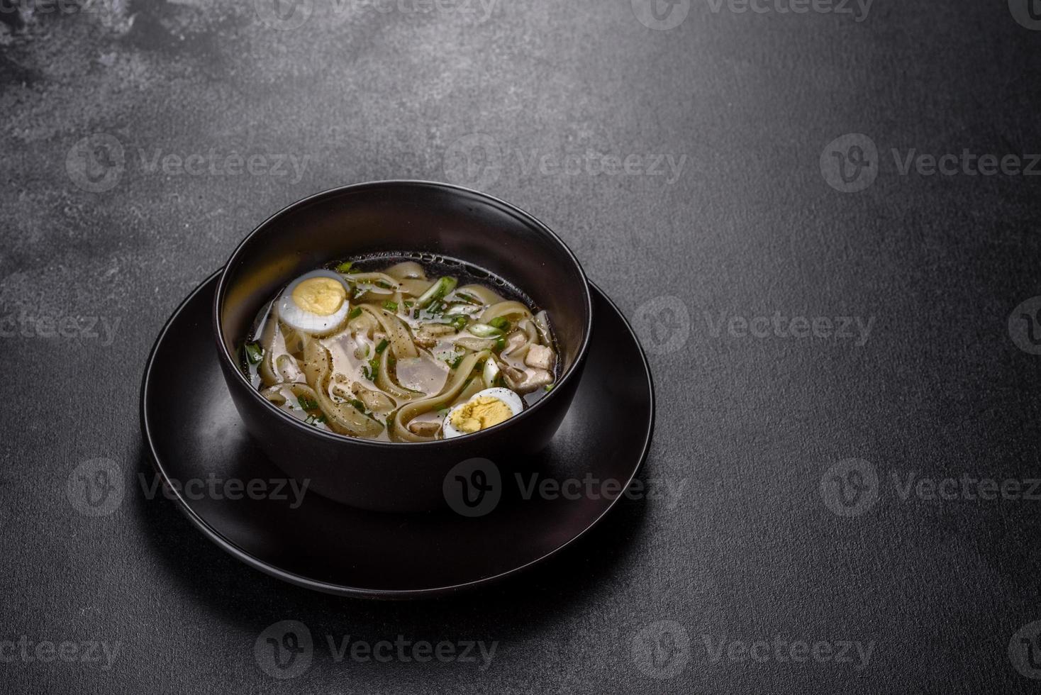 Deliciosa sopa caliente fresca con fideos y huevo de codorniz en una placa negra foto