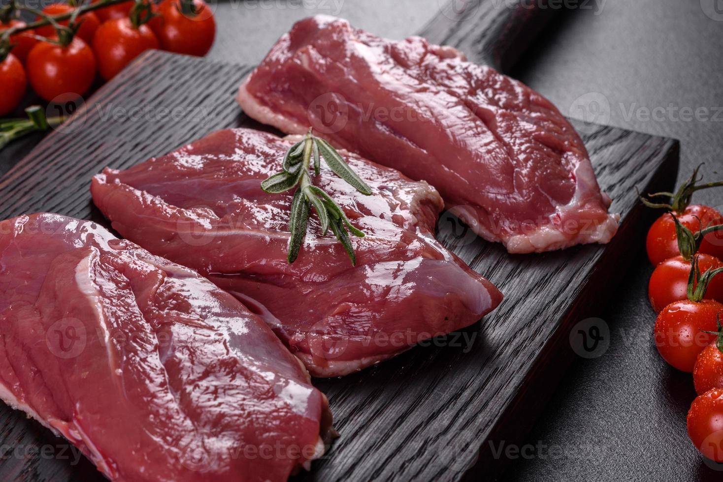 Raw duck breast with herbs and spices on a dark concrete background photo