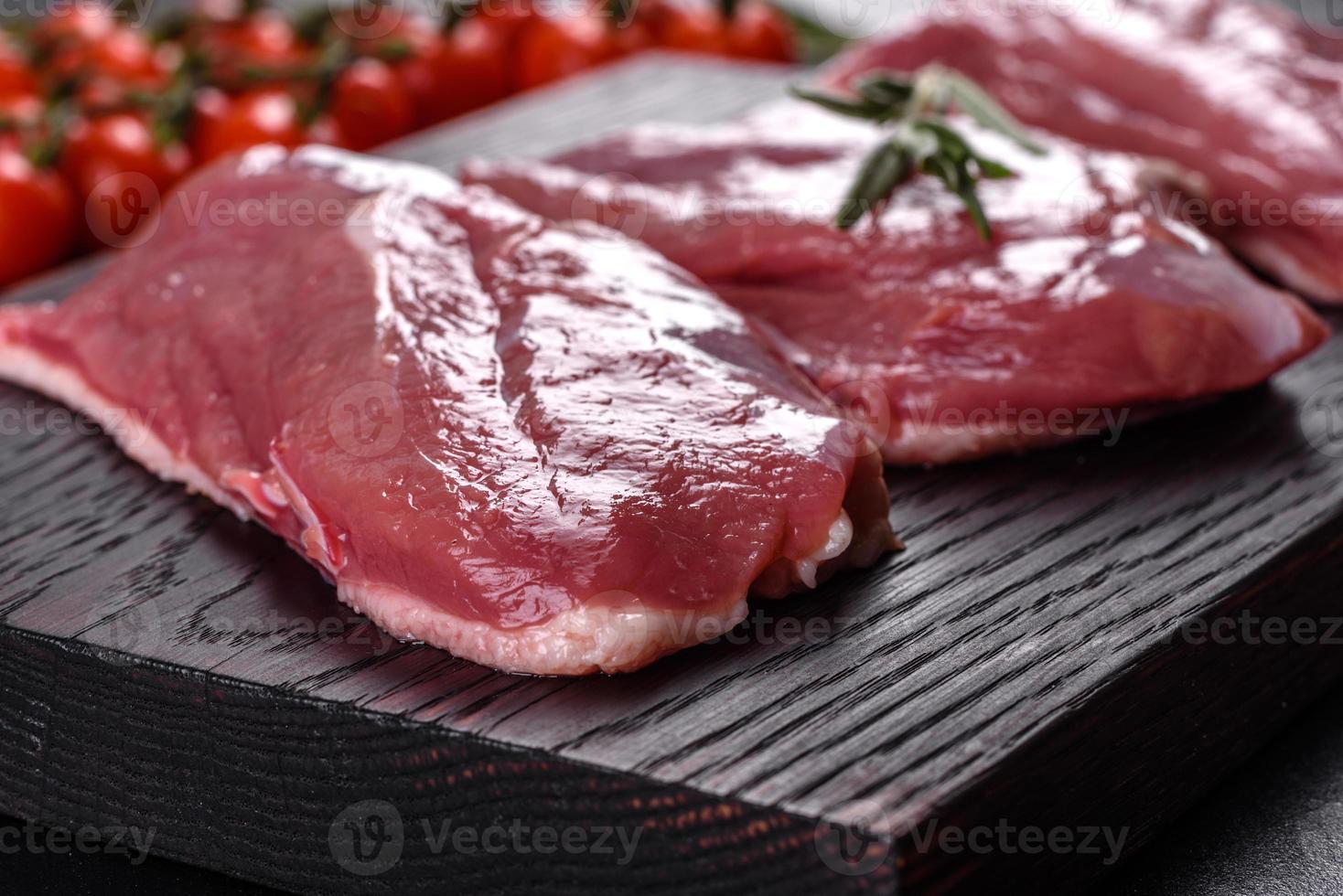 Raw duck breast with herbs and spices on a dark concrete background photo