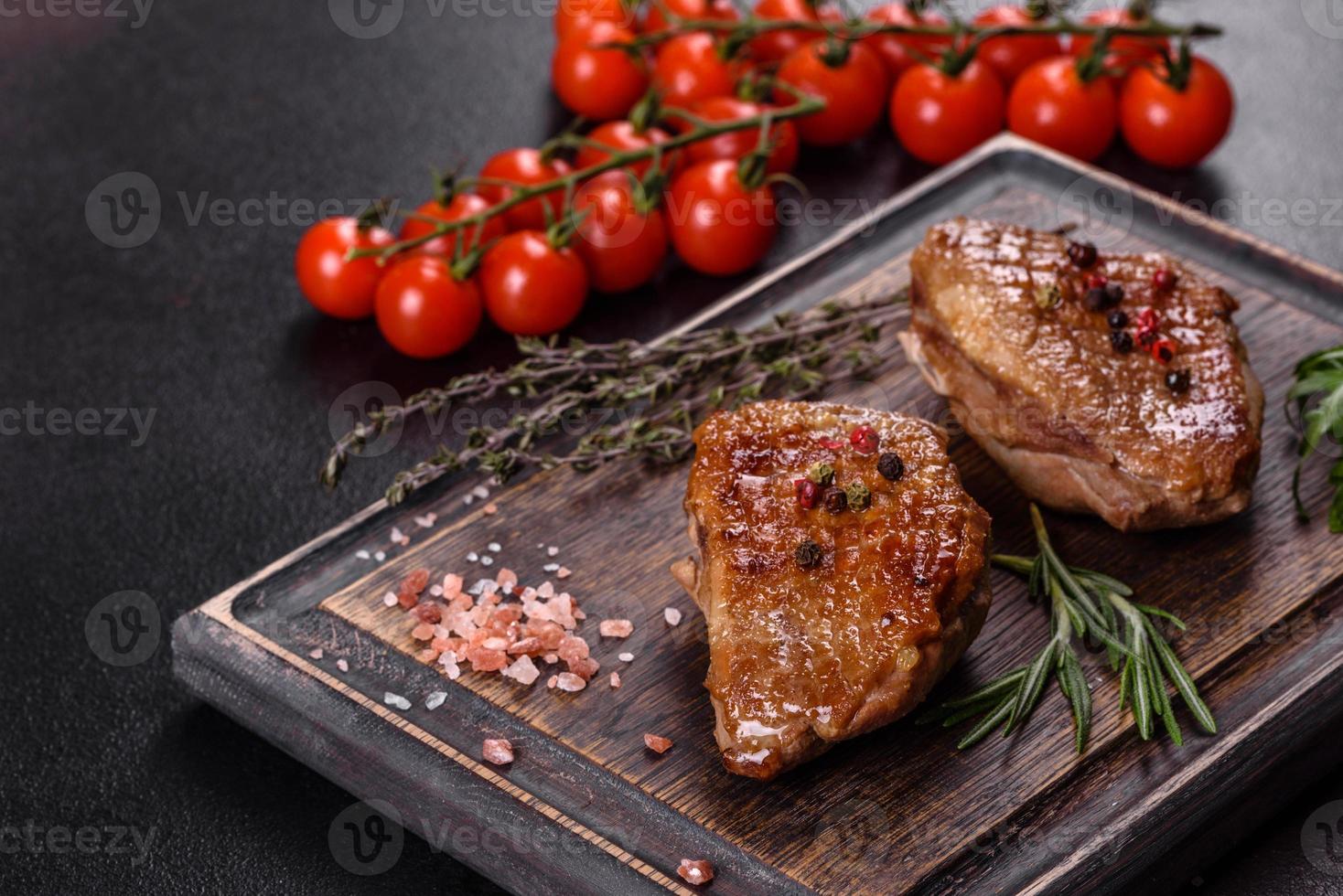 Baked duck breast with herbs and spices on a dark concrete background