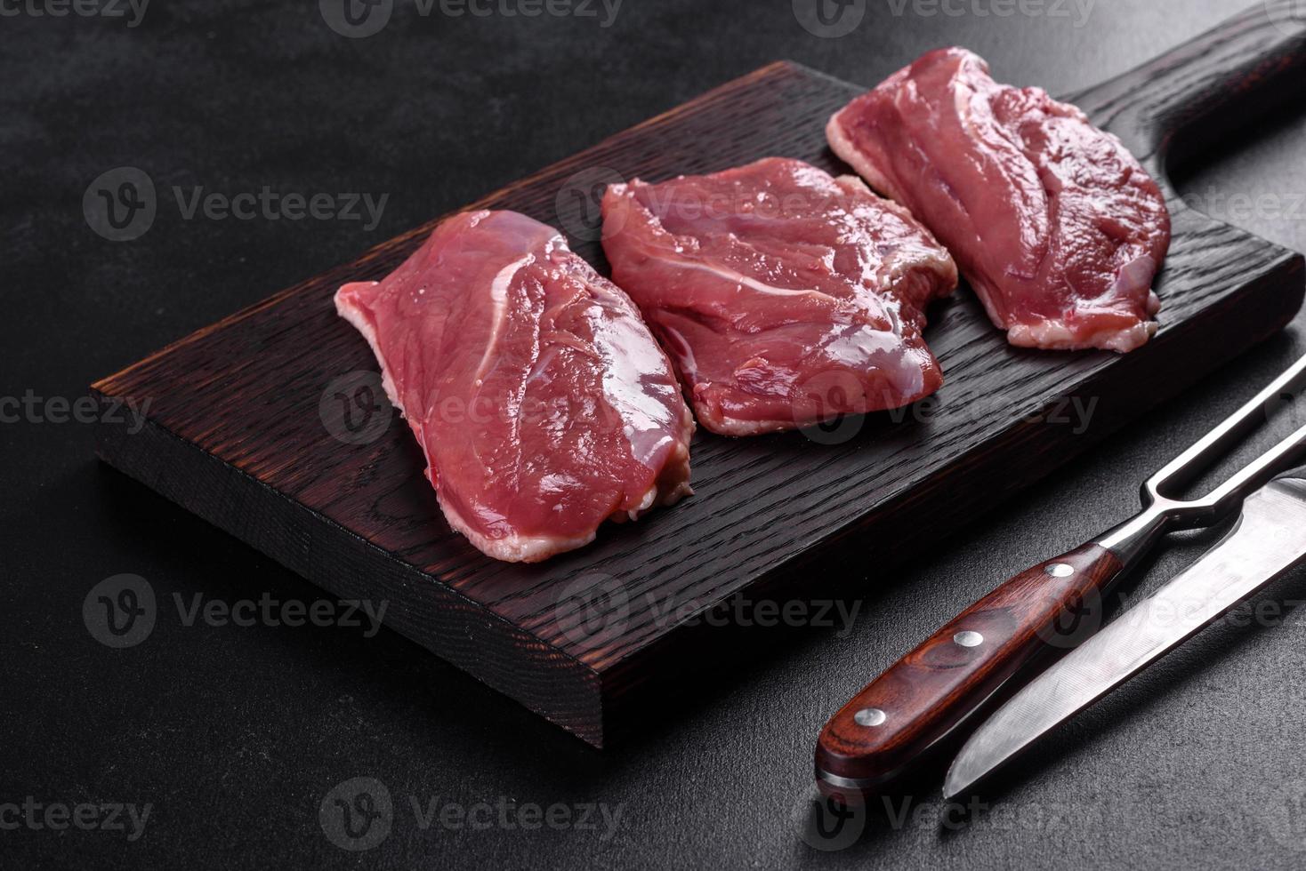 Raw duck breast with herbs and spices on a dark concrete background photo