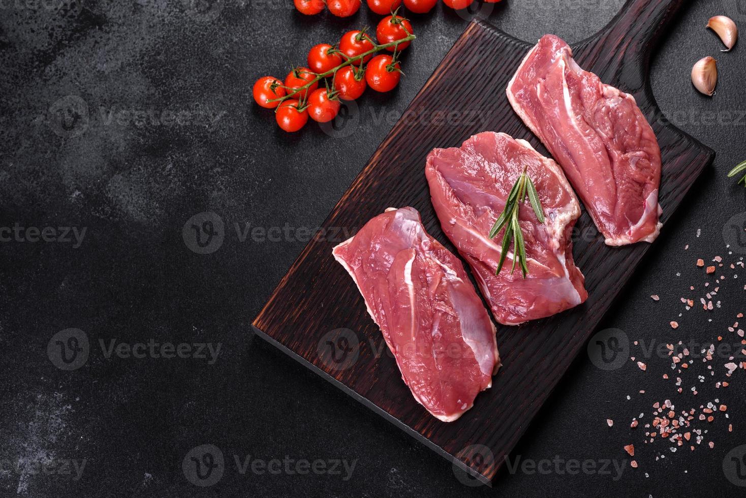 Raw duck breast with herbs and spices on a dark concrete background photo