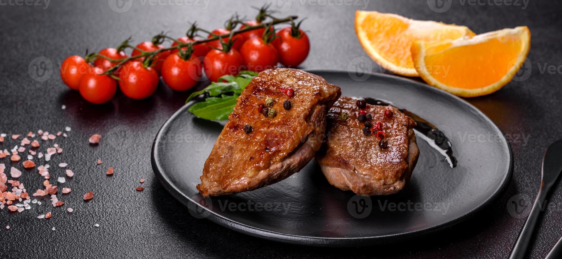 Baked duck breast with herbs and spices on a dark concrete background photo