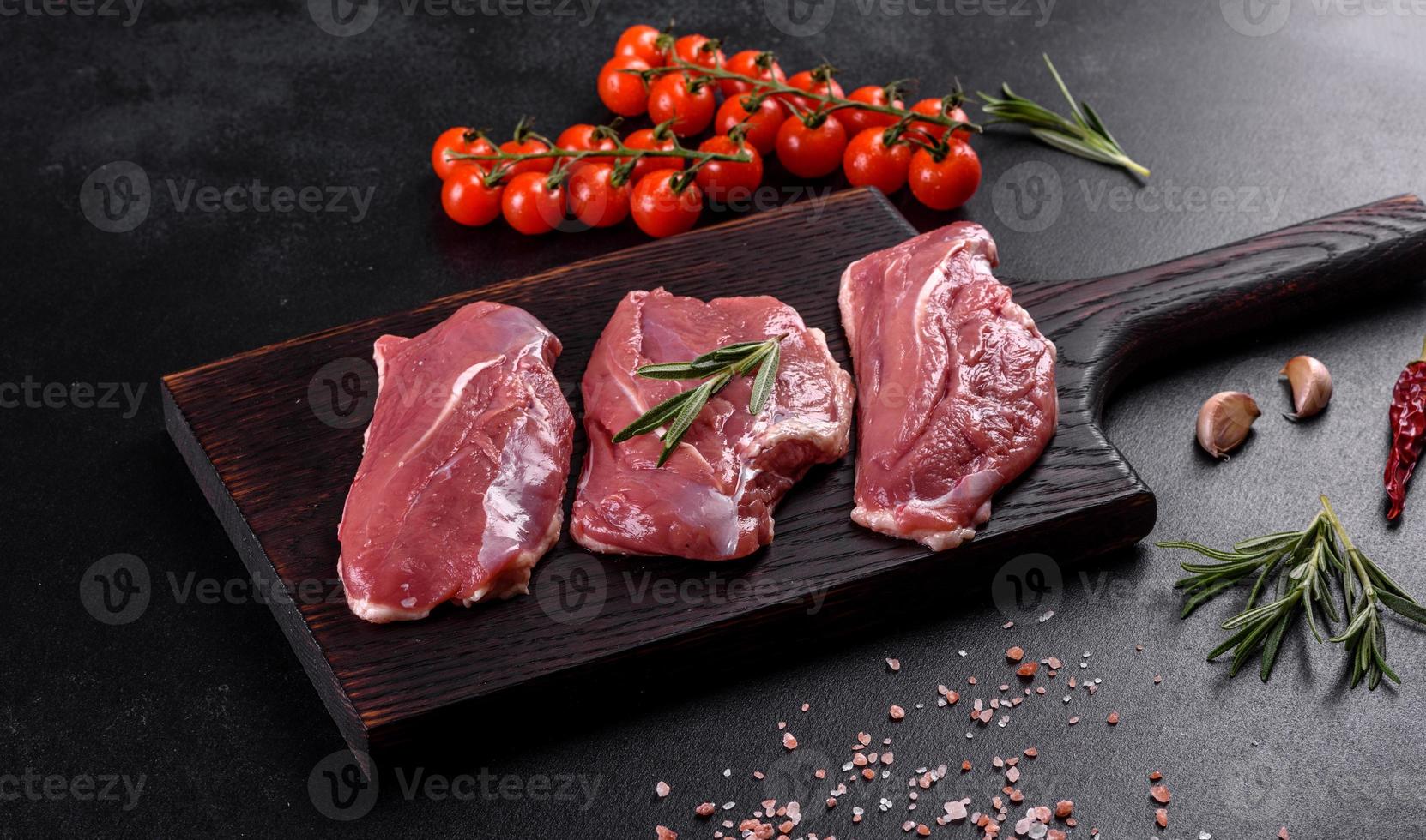 Raw duck breast with herbs and spices on a dark concrete background photo