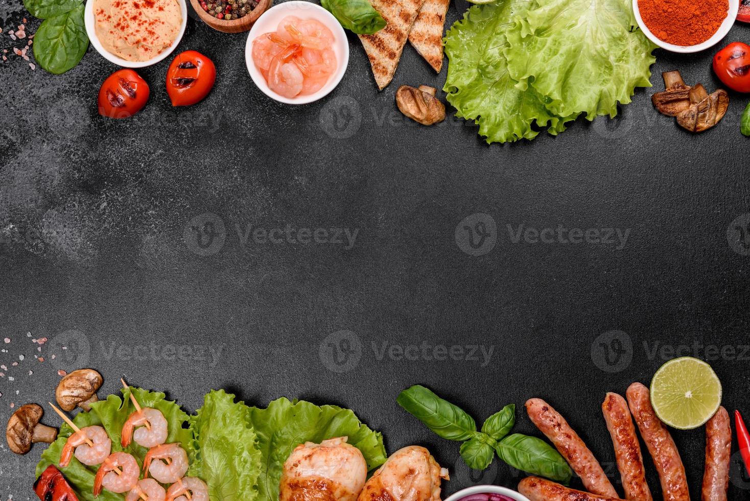 Composition of sausages, chicken, pork and shrimp prepared on grill, as well as vegetables prepared on grill with spices and herbs photo