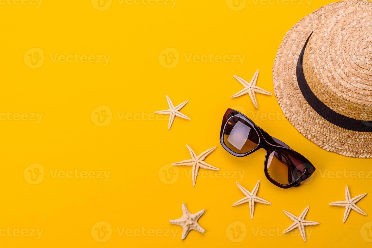 Glasses and hat with shells and sea stars on a colored background photo