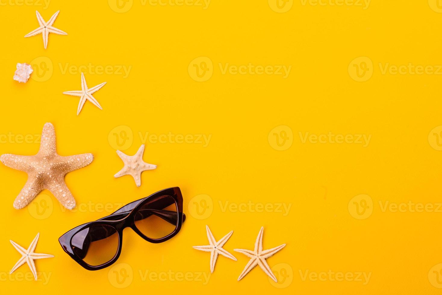 Glasses and hat with shells and sea stars on a colored background photo