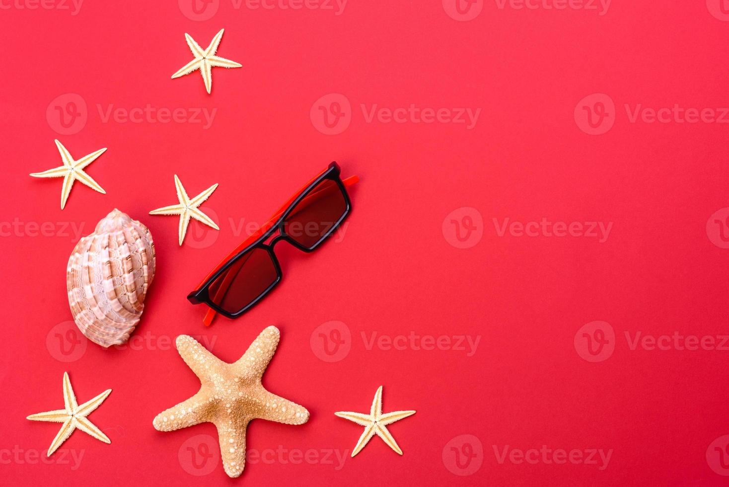 Glasses and hat with shells and sea stars on a colored background photo