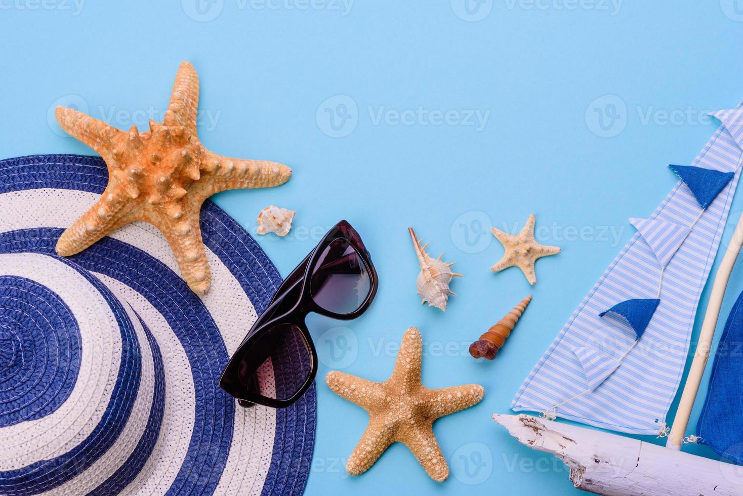 Glasses and hat with shells and sea stars on a colored background photo