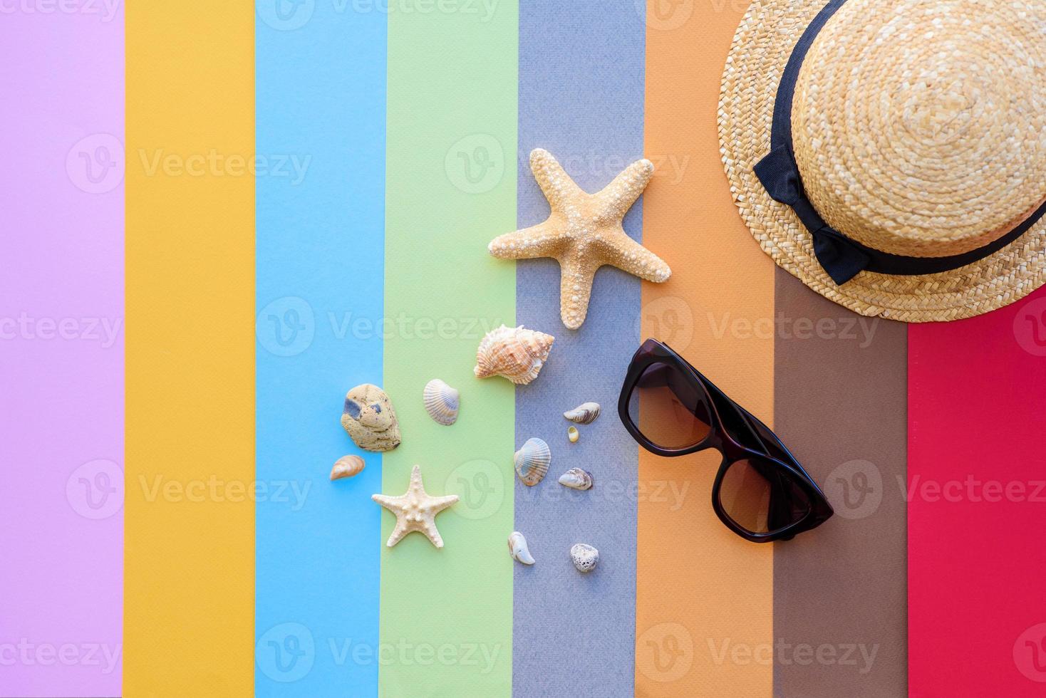 Glasses and hat with shells and sea stars on a colored background photo